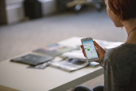 Person sitzt mit Smartphone in der Hand an einem Tisch.