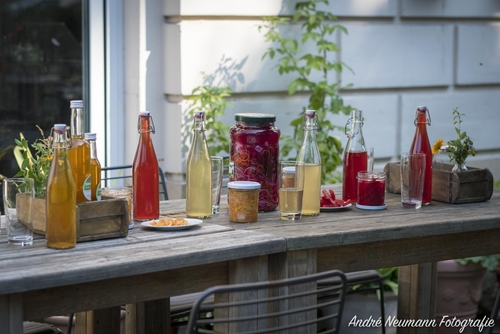 Bunte Gläser mit fermentiertem Gemüse auf einem Gartentisch im Freien