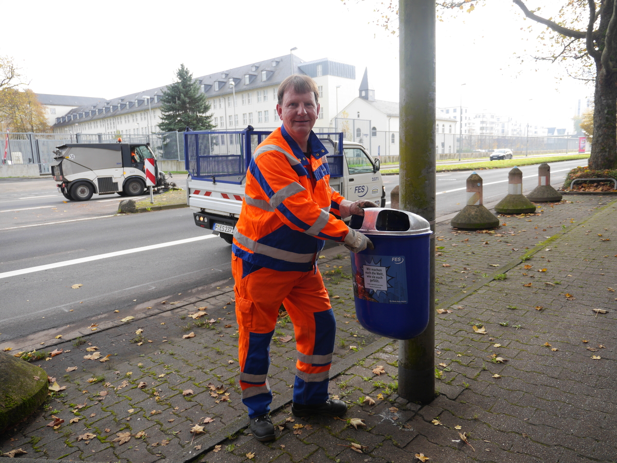 FES-Mitarbeiter leert Papierkorb am Straßenrand
