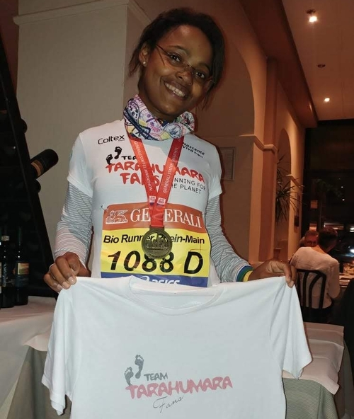 Kind mit Medaille und Startnummer präsentiert stolz ein weißes T-Shirt mit der Aufschrift „Tarahumara“.