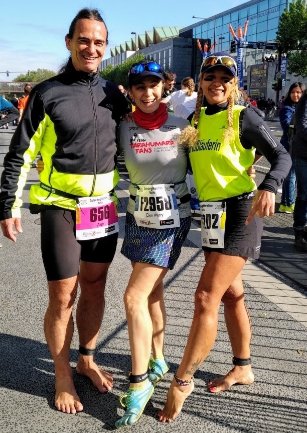 Drei Läufer:innen in Sportkleidung stehen lächelnd nebeneinander bei einem Lauf-Event