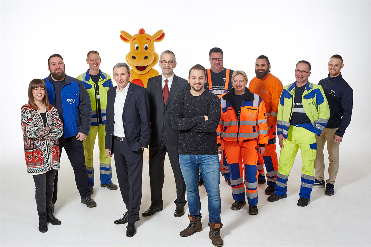 Gruppe von Mitarbeitenden in unterschiedlicher Arbeitskleidung vor weißem Hintergrund