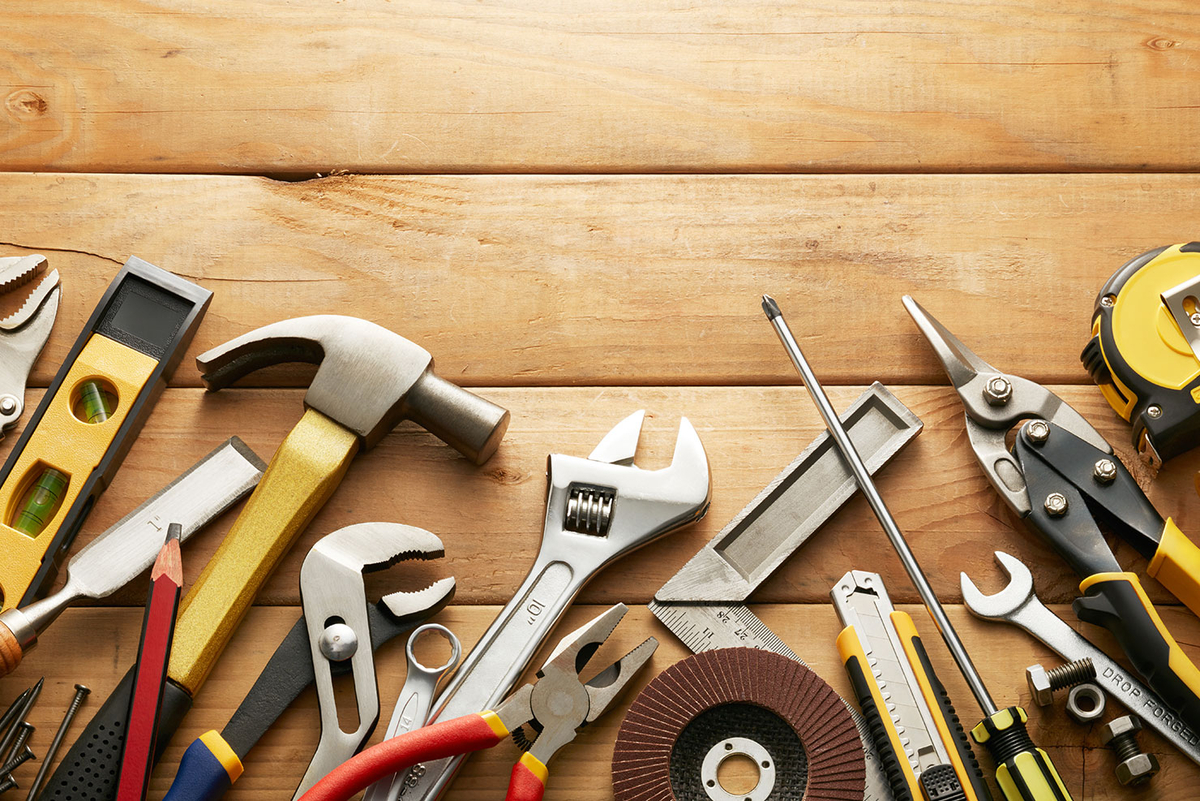 Diverse Werkzeuge liegen auf einem hölzernen Hintergrund.