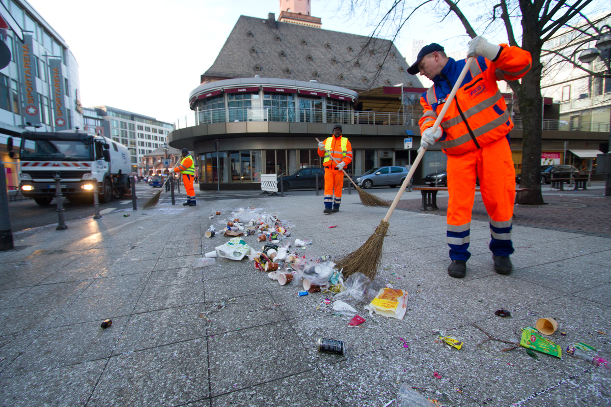 FES-Mitarbeiter kehren Straße mit Besen